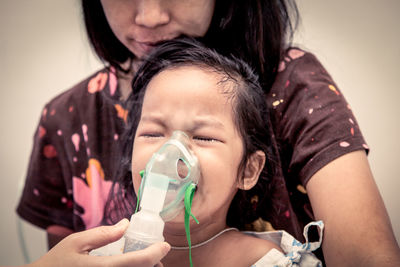 Cropped image of doctor putting mask on crying girl