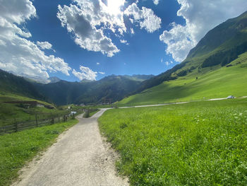 Road amidst green landscape and mountains against sky