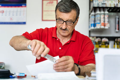 Mid adult man looking away while holding camera on table