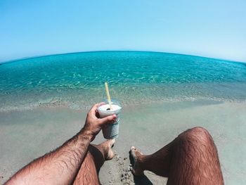 Midsection of person holding sea against clear sky