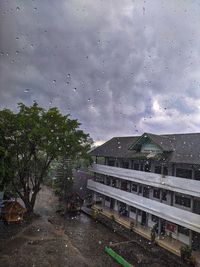 Wet road by trees against sky during rainy season