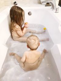 High angle view of siblings in bathtub at home