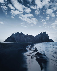 Scenic view of sea by mountains against sky