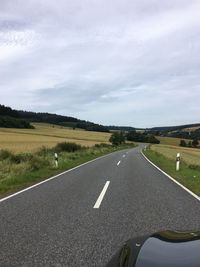 Scenic view of country road on field against sky