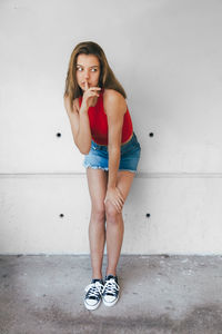 Portrait of young woman standing against wall