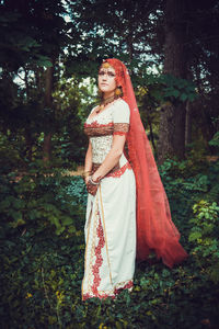 Portrait of woman standing by tree in forest