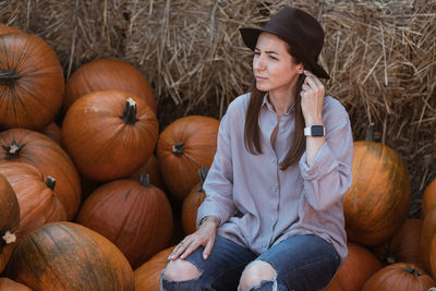 Full length of woman sitting by pumpkin