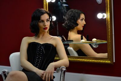 Beautiful woman wearing corset sitting by mirror