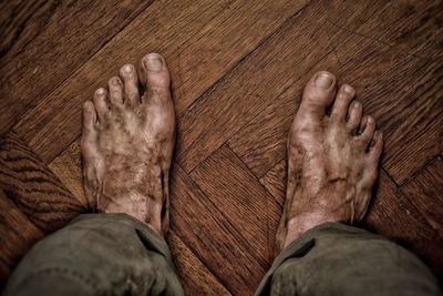 Low section of man standing on hardwood floor