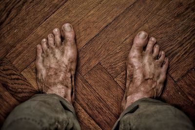 Low section of man wearing shoes on hardwood floor