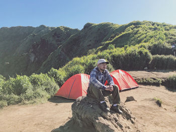 Rear view of woman sitting on mountain against sky