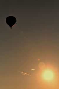 Silhouette hot air balloon flying against sky during sunset