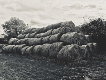 Stack of hay bales on field against sky