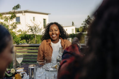 Happy woman enjoying dinner with friends in back yard