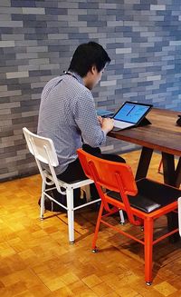 Rear view of man using laptop on table