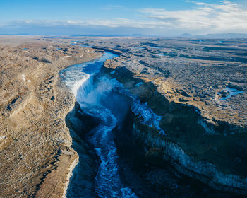Aerial view of river flowing through land against sky
