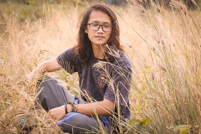 Portrait of young woman sitting on field