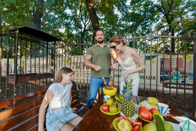 Full length of mother and girl sitting on fruits