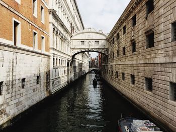 Canal amidst city against sky