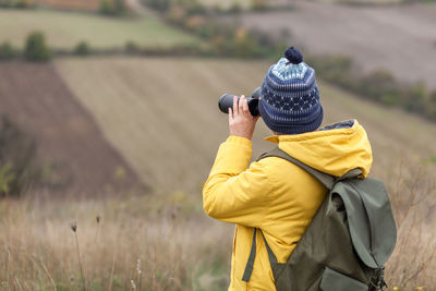 Rear view of person photographing on field