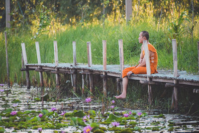 Side view of woman sitting on grassland