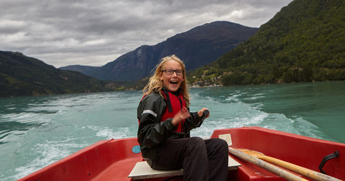 Portrait of cheerful girl sitting on boat at lake