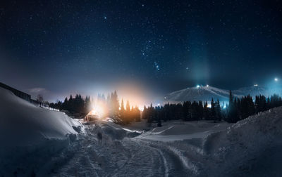 Panoramic view of illuminated snowcapped mountains against sky at night