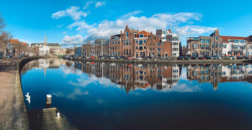 Reflection of buildings in river against blue sky