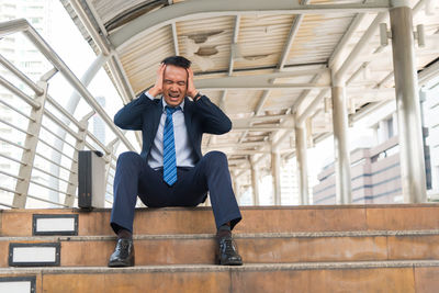 Full length of frustrated businessman sitting on steps