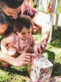 Baby toddler is unwrapping a present with daddy