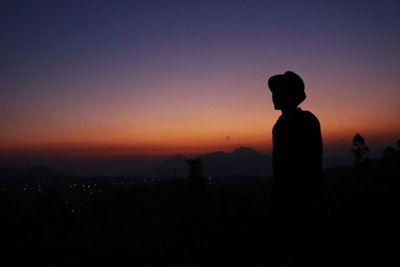 Silhouette man looking at sunset