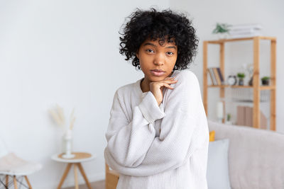 Portrait of young woman standing against white background