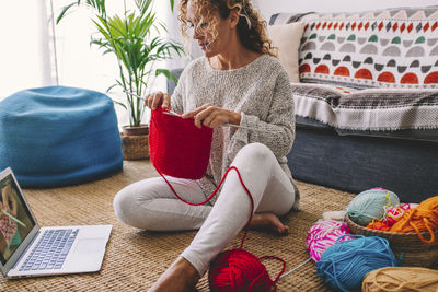 Low section of woman sitting on sofa at home