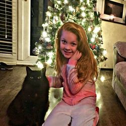 Girl sitting on christmas tree at home
