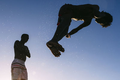 Low angle view of silhouette person standing against clear blue sky