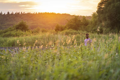 Man standing on field against sky during sunset