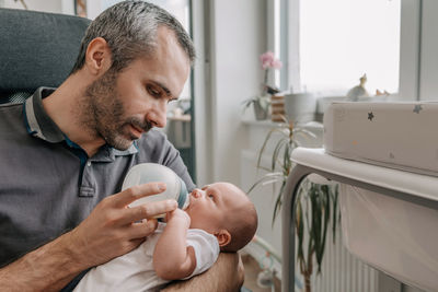 Father feeding baby with bottle of baby formula