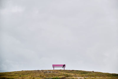 Bench on field against sky