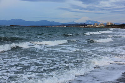 Sea waves rushing towards shore against sky