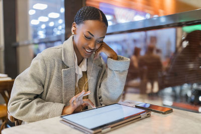 Teenage girl using touch screen laptop sitting at cafe