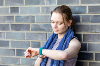 Young woman looking away against wall