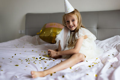 Portrait of young woman using mobile phone while lying on bed at home