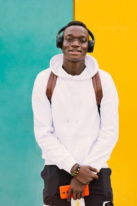 Portrait of a smiling young man standing against wall