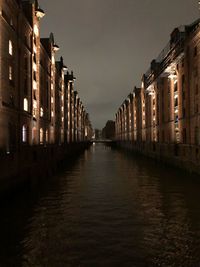 Canal amidst illuminated buildings against sky at night