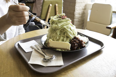 Midsection of person holding ice cream on table