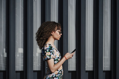 Young woman standing against wall