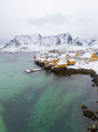 Aerial view of snowcapped mountains by sea against sky
