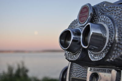 Close-up of coin-operated binoculars against sky during sunset