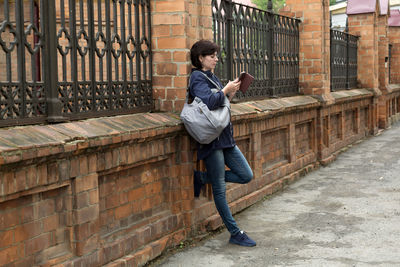 A brunette woman street with a smile looks into the phone texting with her lover.