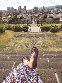 Low section of woman sitting on road in city